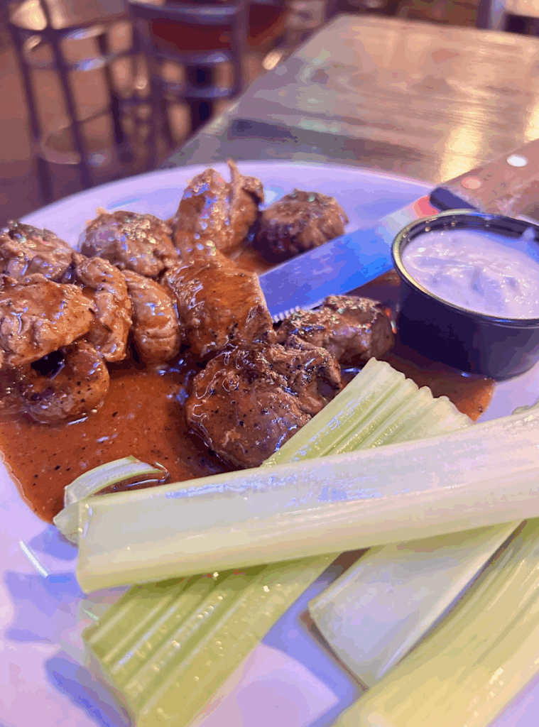 A plate full of spicy Thai wings with celery and bleu cheese sauce